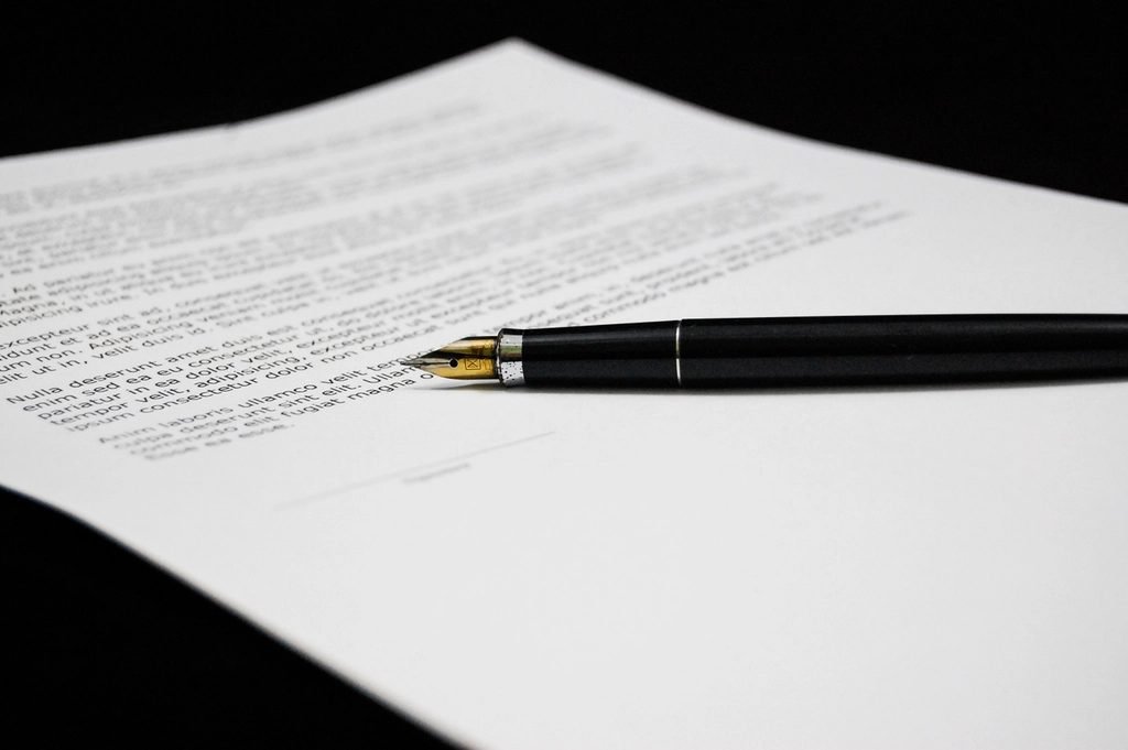 A printed document with a fountain pen resting across it, nib toward the text
